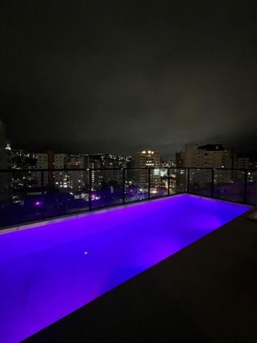 a purple swimming pool on the roof of a building at night at Royal Luxury 305 in Poços de Caldas