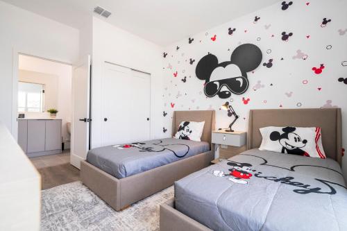 a bedroom with two beds and a mickey mouse wall decal at Doppio Westside in Orlando