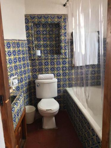 a bathroom with a toilet and a bath tub at Hotel Mi Casita in Taxco de Alarcón