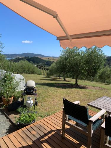 a deck with a picnic table and a grill on a field at Private Olive Grove Studio in Mangonui
