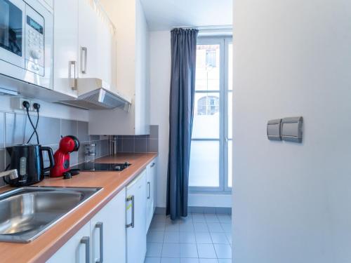 une cuisine avec des armoires blanches, un évier et une fenêtre dans l'établissement Charming studio- 2P- Jardin des plantes Austerlitz, à Paris