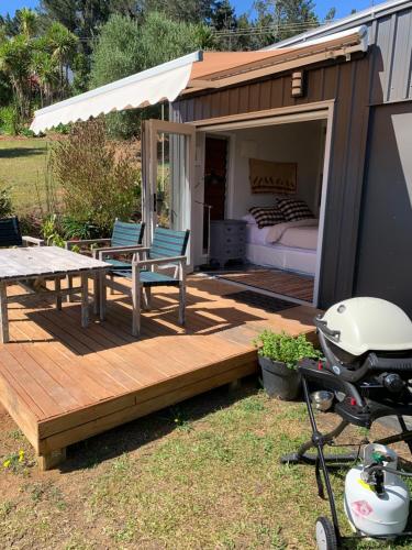 a tiny house with a bed and a table and a grill at Private Olive Grove Studio in Mangonui