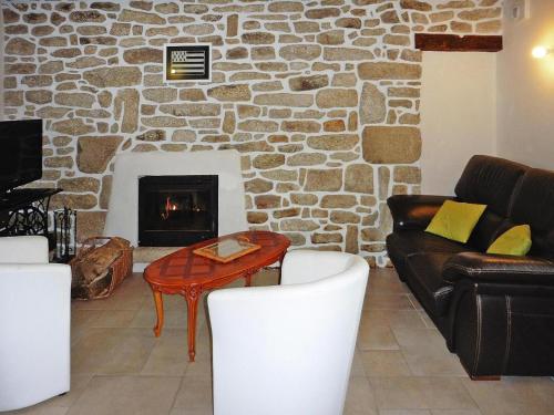 a living room with a stone fireplace and a table and chairs at Stone House near Torche Beach in Plobannalec-Lesconil