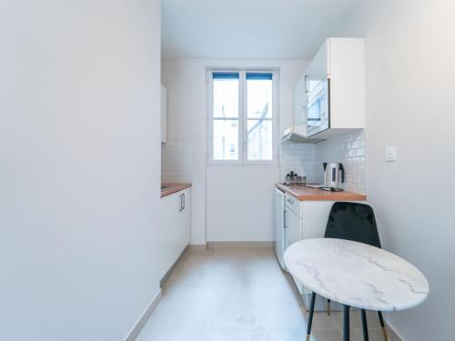 une petite cuisine blanche avec une table et une fenêtre dans l'établissement Charming studio- 2P- Jardin des plantes Austerlitz, à Paris
