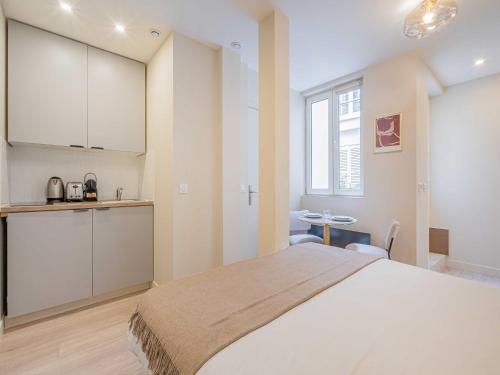 une chambre avec un grand lit blanc et une cuisine dans l'établissement Cosy studio for 2P - Le Bon Marché, à Paris