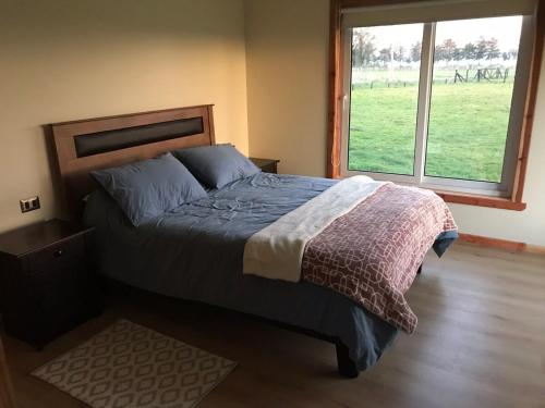 a bedroom with a bed and a large window at Linda Casa en parcela, 3 minutos de frutillar Bajo in Frutillar