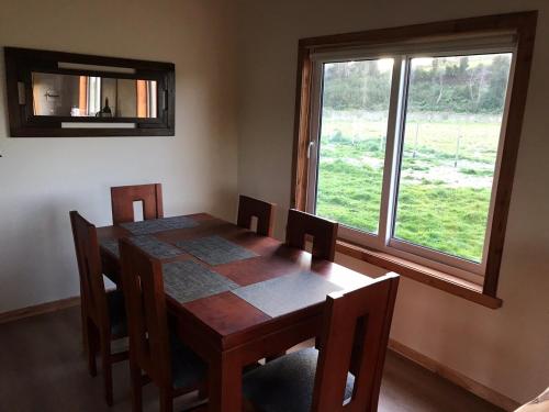 a dining room with a table and chairs and a window at Linda Casa en parcela, 3 minutos de frutillar Bajo in Frutillar