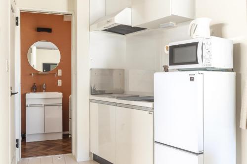 a kitchen with a white refrigerator and a microwave at Home Suite Home Ikejiri - Shibuya 1 Stop! Sleek Confort with Washer and Dryer in Tokyo