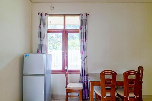 a kitchen with a table and a refrigerator and a window at Urbanview Resort Villa Andy Tour Cisarua Puncak in Sampal 2