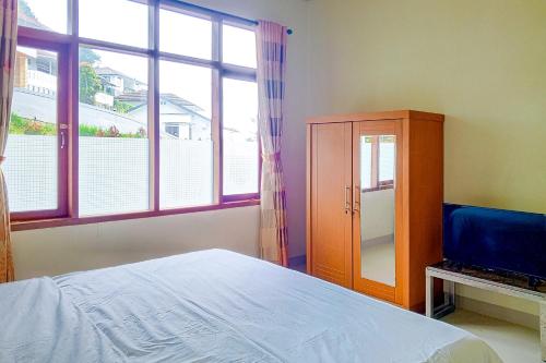 a bedroom with a bed and a cabinet and a window at Urbanview Resort Villa Andy Tour Cisarua Puncak in Sampal 2