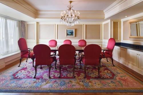 a dining room with a table and red chairs at RIHGA Royal Hotel Osaka, Vignette Collection by IHG in Osaka