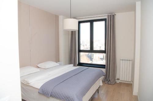 Un dormitorio blanco con una cama y una ventana grande. en Belgrade Waterfront Promenade, en Belgrado