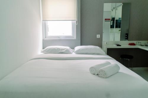a large white bed with two white towels on it at Nice Studio Apartment at Aeropolis Residence near CGK Airport By Travelio in Tangerang