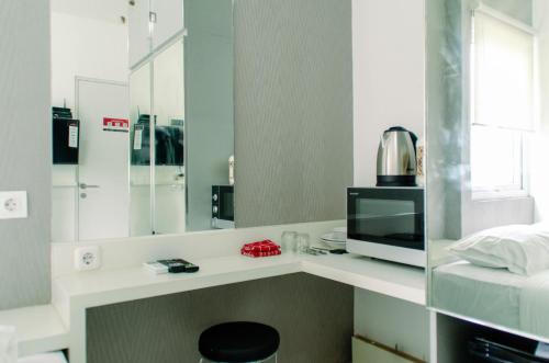 a bathroom with a counter with a sink and a mirror at Nice Studio Apartment at Aeropolis Residence near CGK Airport By Travelio in Tangerang