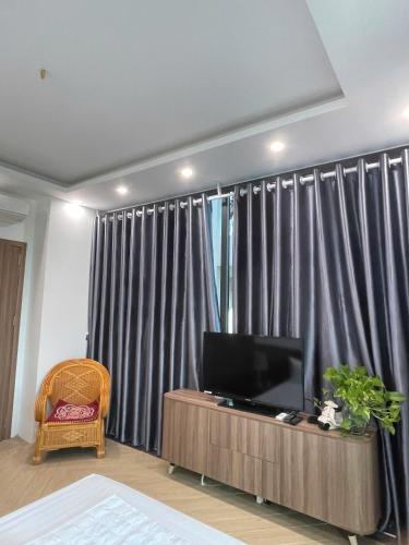 a living room with a flat screen tv in front of curtains at The Blue Villa in Gò Ba Quần
