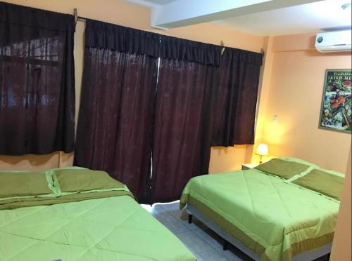 a bedroom with two green beds and a window at Casa central in San Juan del Sur
