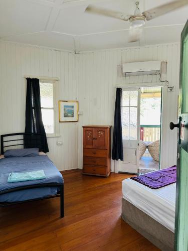 a bedroom with two beds and a wooden floor at Exchange Hotel Backpacker Resort in Mossman
