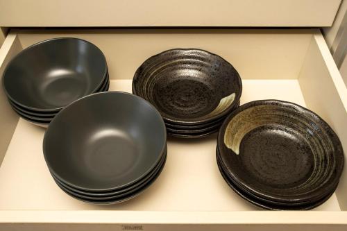 four black plates and bowls sitting on a shelf at 天然温泉-富士山パノラマビュー-プライベートデッキで非日常体験を-伊豆の温泉付き貸別荘-中伊豆noie in Izu