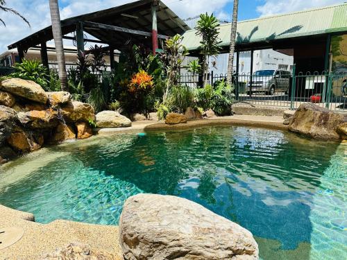 a large pool of water with rocks in front of a building at Exchange Hotel Backpacker Resort in Mossman