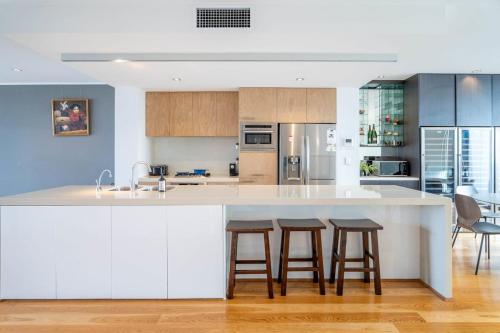 a kitchen with a large white island with bar stools at Luxury 4B Docklands Penthouse water city views in Melbourne