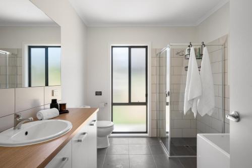 a white bathroom with a sink and a toilet at The Sandbar Stay - Wi-Fi, BBQ, Parking in Middleton
