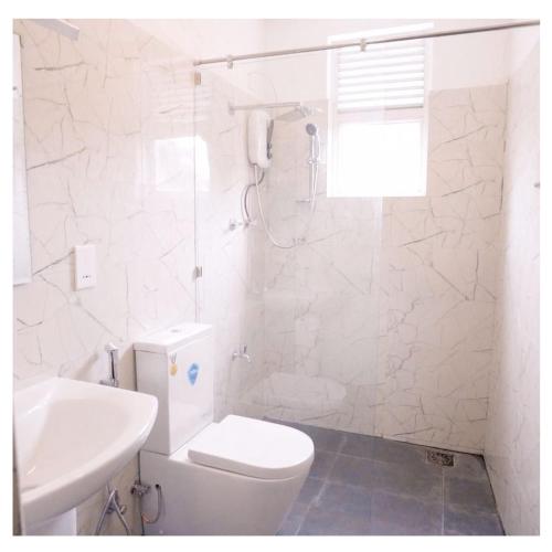 a white bathroom with a toilet and a sink at Diyawanna Villa - Deluxe Twin Room in Colombo in Sri Jayewardenepura Kotte