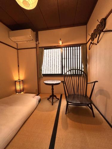 a room with a bed and a chair and a table at Guest House Oumi in Kyoto