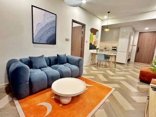a living room with a blue couch and a table at THE METROPOLE Apartment Complex OPERA-GALLERIA-CREST in Ho Chi Minh City