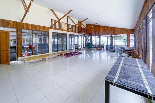 a large room with a white tile floor and glass windows at RedDoorz Plus at Pantai Sayangheulang Garut in Cilauteureun