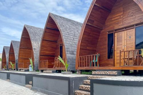 a row of cottages with wood at RedDoorz Plus at Pantai Sayangheulang Garut in Cilauteureun