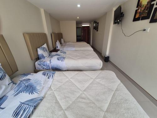 two beds in a room with blue and white at Hotel Valle Andino in Cusco