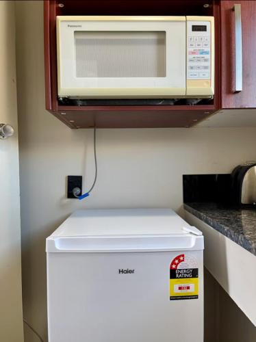 a microwave on top of a refrigerator in a kitchen at Heart of Christchurch City Studio in Christchurch