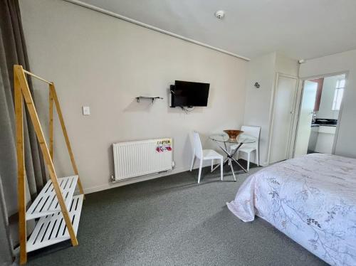 Un dormitorio con una cama, una mesa y un televisor. en Heart of Christchurch City Studio, en Christchurch