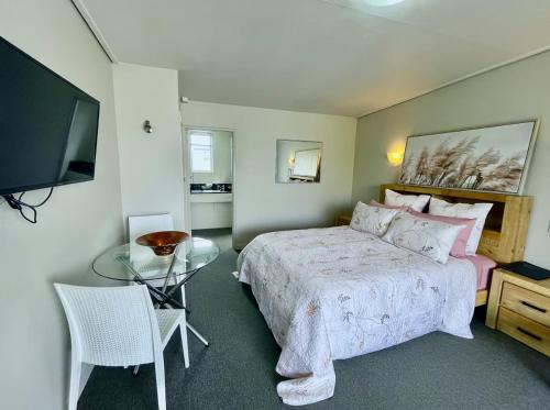 a bedroom with a bed and a table and a television at Heart of Christchurch City Studio in Christchurch
