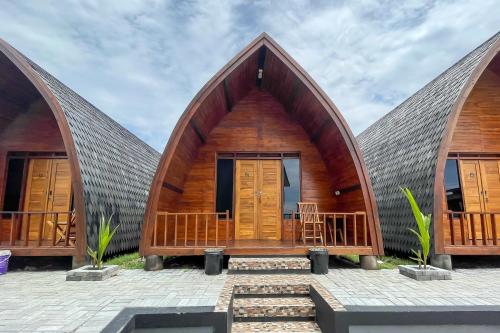 a house with a thatched roof and wooden doors at RedDoorz Plus at Pantai Sayangheulang Garut in Cilauteureun