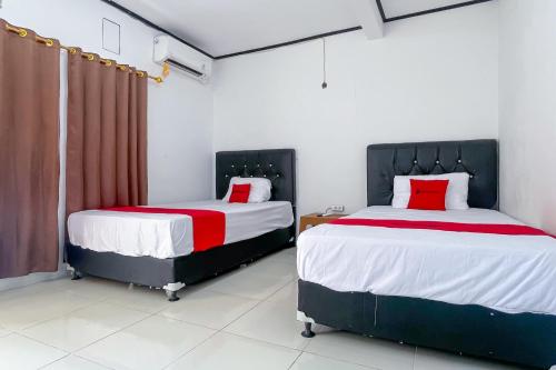 a bedroom with two beds with red and white sheets at RedDoorz Plus at Pantai Sayangheulang Garut in Cilauteureun