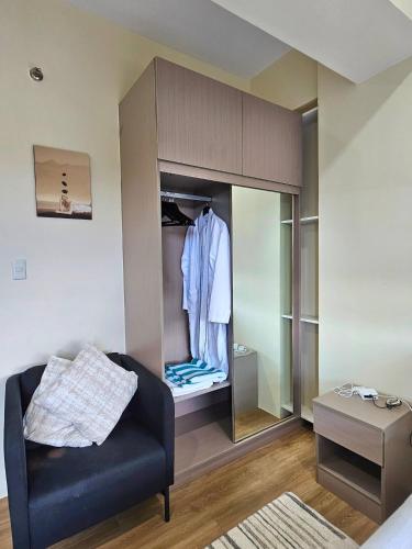 a living room with a black couch and a closet at Elegant Studio with balcony unit 625 - 6th floor - near Ateneo De Cebu - High speed internet - Northwoods Place in Mandaue City