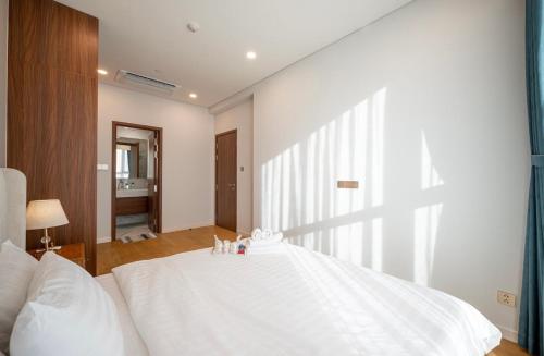 a large white bed in a bedroom with a window at THE METROPOLE Apartment Complex OPERA-GALLERIA-CREST in Ho Chi Minh City
