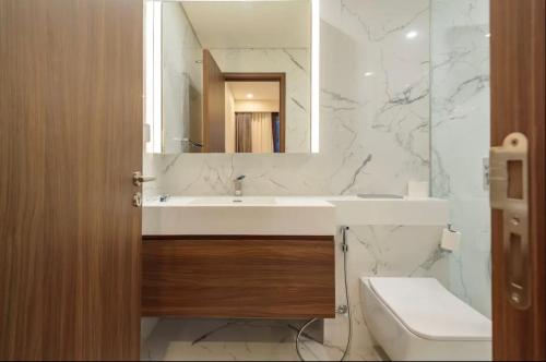 a bathroom with a sink and a mirror and a toilet at THE METROPOLE Apartment Complex OPERA-GALLERIA-CREST in Ho Chi Minh City
