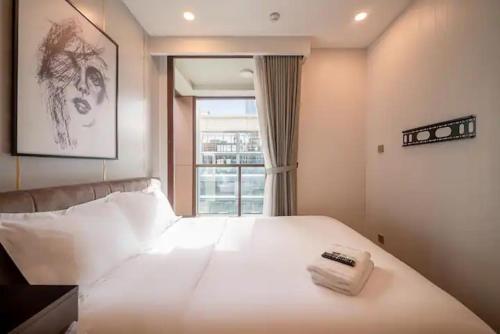 a bedroom with a large white bed with a window at THE METROPOLE Apartment Complex OPERA-GALLERIA-CREST in Ho Chi Minh City