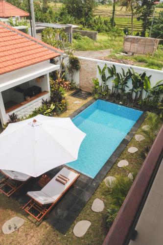 an umbrella and chairs next to a swimming pool at Evara Lifestyle Villa by Aayan in Tabanan
