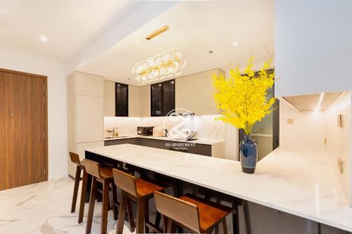 a kitchen with a counter with chairs and a vase with yellow flowers at THE METROPOLE Apartment Complex OPERA-GALLERIA-CREST in Ho Chi Minh City