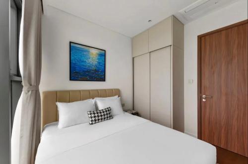 a bedroom with a white bed and a wooden door at THE METROPOLE Apartment Complex OPERA-GALLERIA-CREST in Ho Chi Minh City