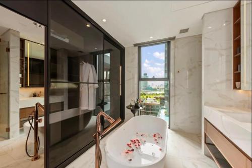 a bathroom with a white tub and a glass wall at THE METROPOLE Apartment Complex OPERA-GALLERIA-CREST in Ho Chi Minh City