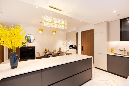 a kitchen with white cabinets and a vase with yellow flowers at THE METROPOLE Apartment Complex OPERA-GALLERIA-CREST in Ho Chi Minh City