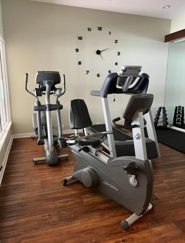 a gym with two exercise bikes and a clock on the wall at Newly Renovated Villa with King Bed and Amenities, 1 mile to Mohegan Sun in Norwich