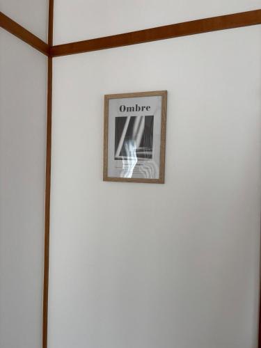 a picture on a white wall with a framed picture at Orange Stay Matsuyama in Matsuyama