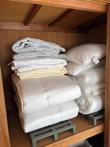 a pile of white pillows on a shelf at Orange Stay Matsuyama in Matsuyama