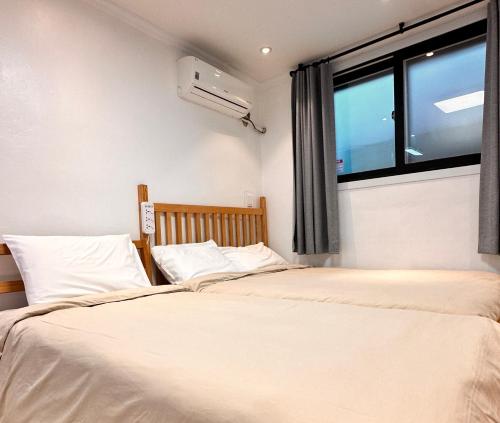 two twin beds in a room with a window at Studio 6 in Seoul