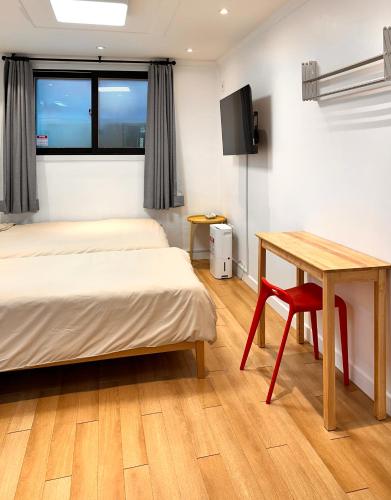 a room with two beds and a desk and a table at Studio 6 in Seoul